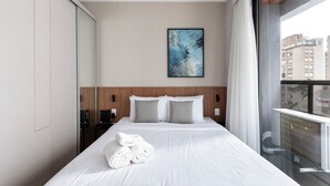 A hotel room with a large bed, a headboard, a painting, and a view of the city through a window. - 360 SP Faria Lima (São Paulo)