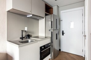 A compact kitchen with a double sink, a built-in oven, and a stainless steel refrigerator. - 360 SP Faria Lima (São Paulo)