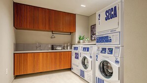A compact laundry room with wooden cabinets, a washing machine, and a dryer. - 360 SP Faria Lima (São Paulo)