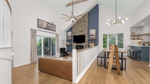 Een moderne woonkamer met houten vloer, een stenen openhaard, een flatscreen televisie en een eethoek met een houten tafel en stoelen.