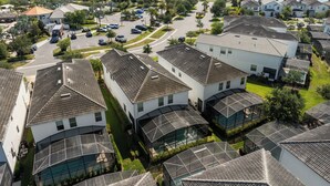 A residential area with modern houses, a parking lot, and a lake in the background. - Kissimmee Retreat  6BR House Sleeps 14 (Kissimmee)
