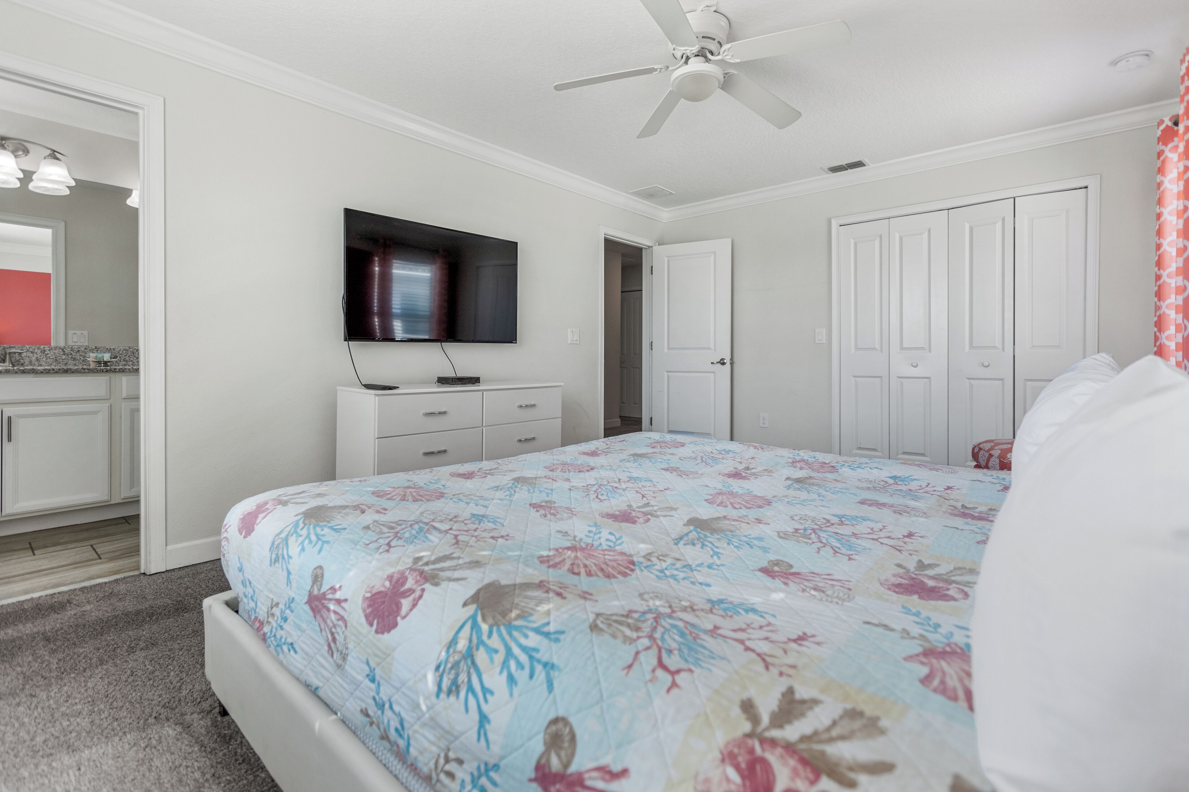A bedroom with a bed, a ceiling fan, a TV, and a wardrobe.
