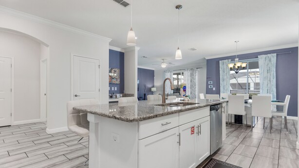 A modern kitchen with white cabinetry, granite countertops, and a central island. - Kissimmee Retreat  6BR House Sleeps 14 (Kissimmee)