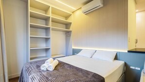 A hotel room with a neatly made bed, a large walk-in closet, and a wall-mounted air conditioner. - Studio With Barbecue 180m From the Beach - Sfr0302 (Bombinhas)