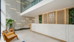 A modern reception area with a high ceiling, a reception desk, and a seating area with a sofa and chairs.