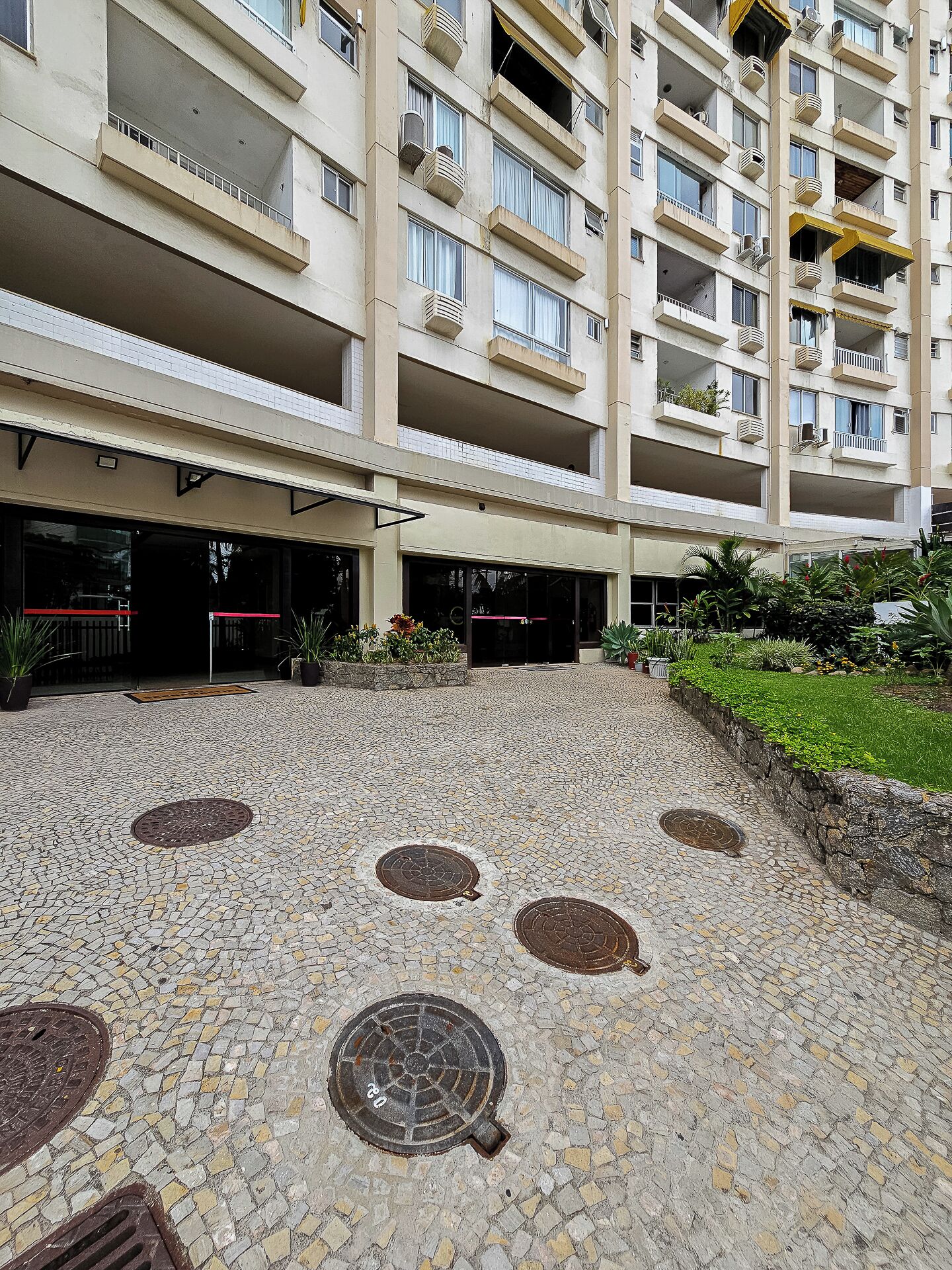 Une cour dallée, entourée d’un immeuble à plusieurs étages doté de balcons et de fenêtres.