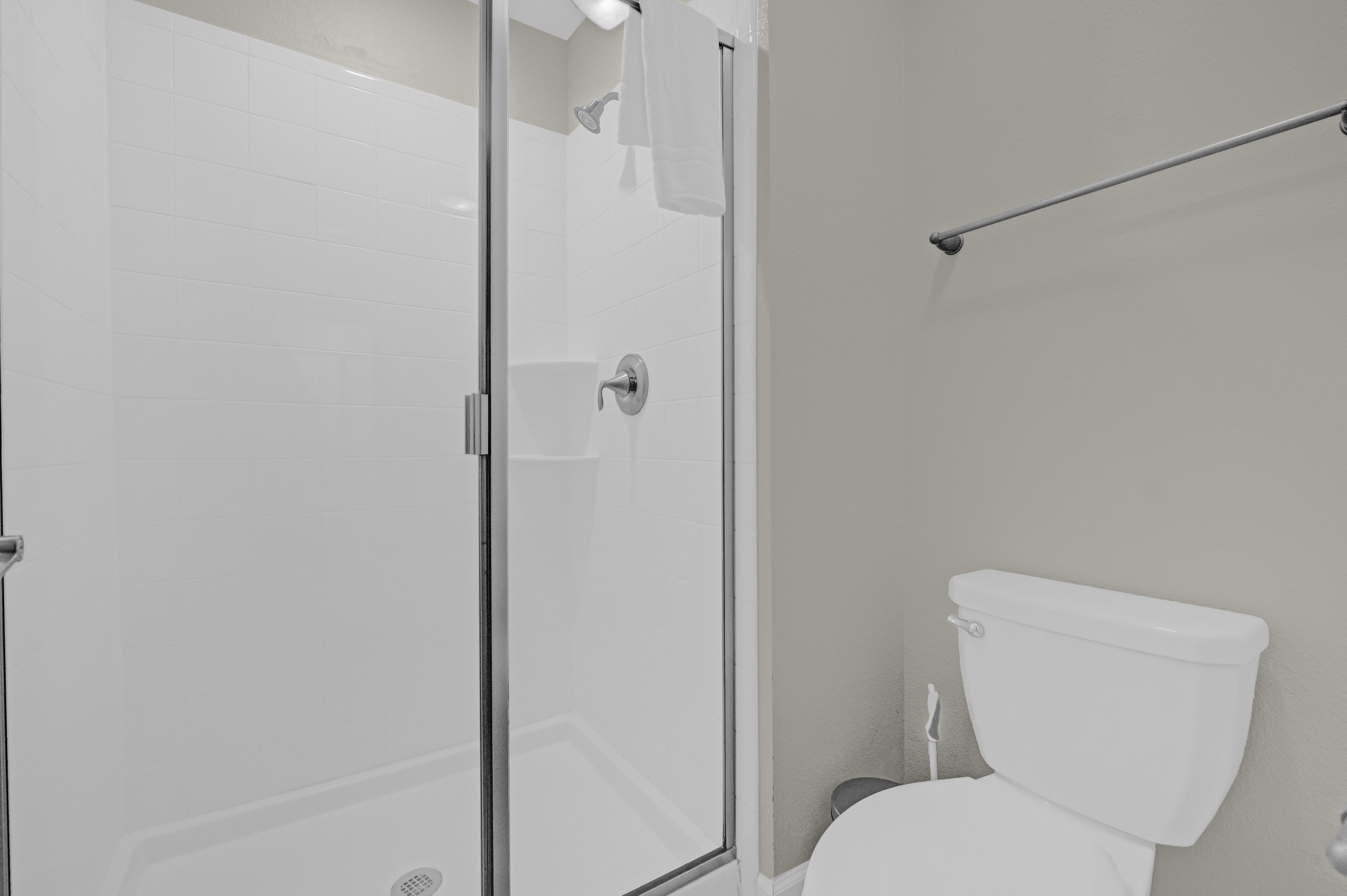 Ein Badezimmer mit Glasdusche, Toilette in Weiß und Handtuchhalter.