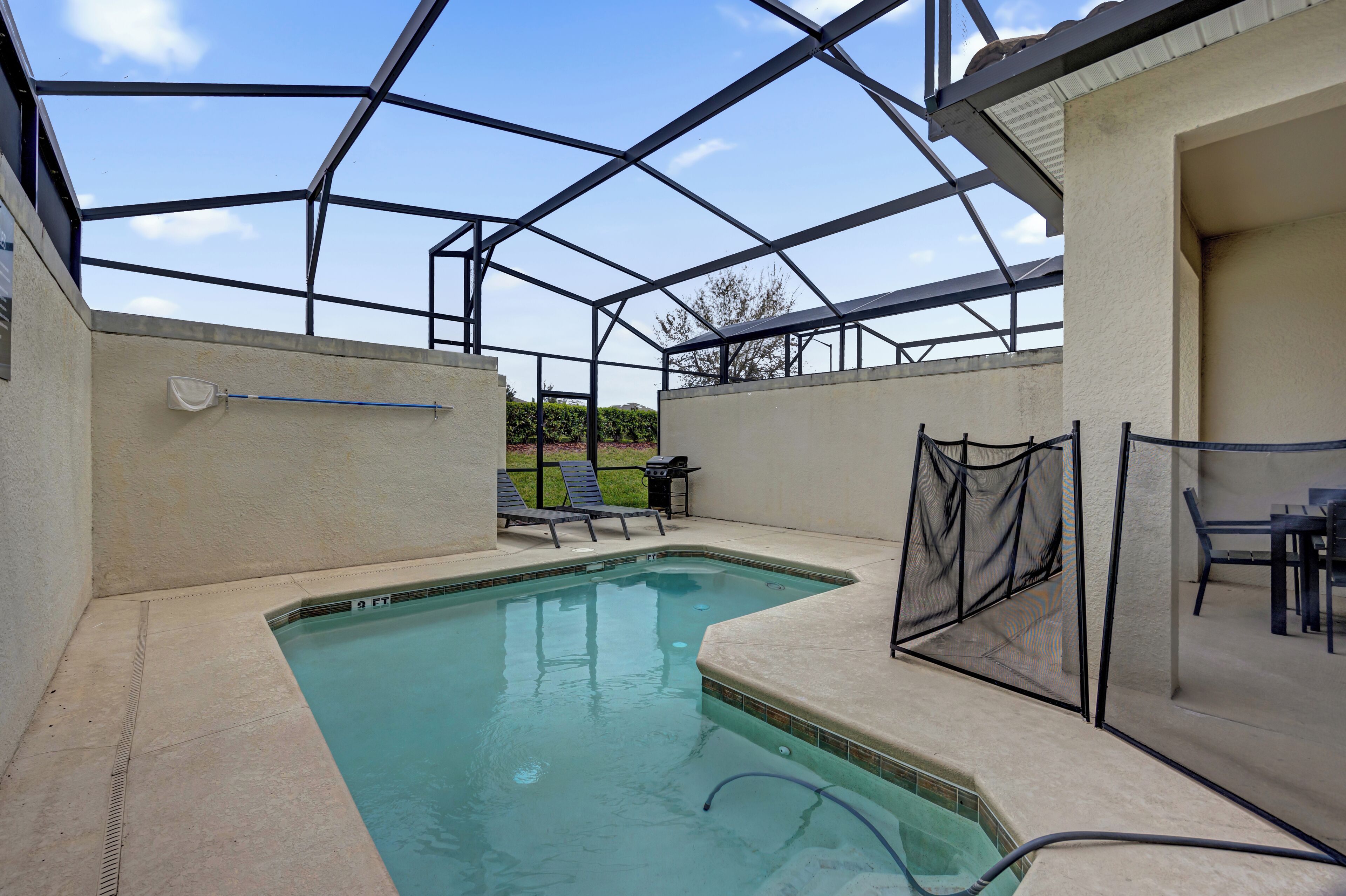 A swimming pool with a covered area, lounge chairs, and a table.