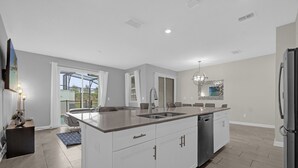 A modern kitchen with white cabinetry, a stainless steel sink, and a built-in dishwasher.