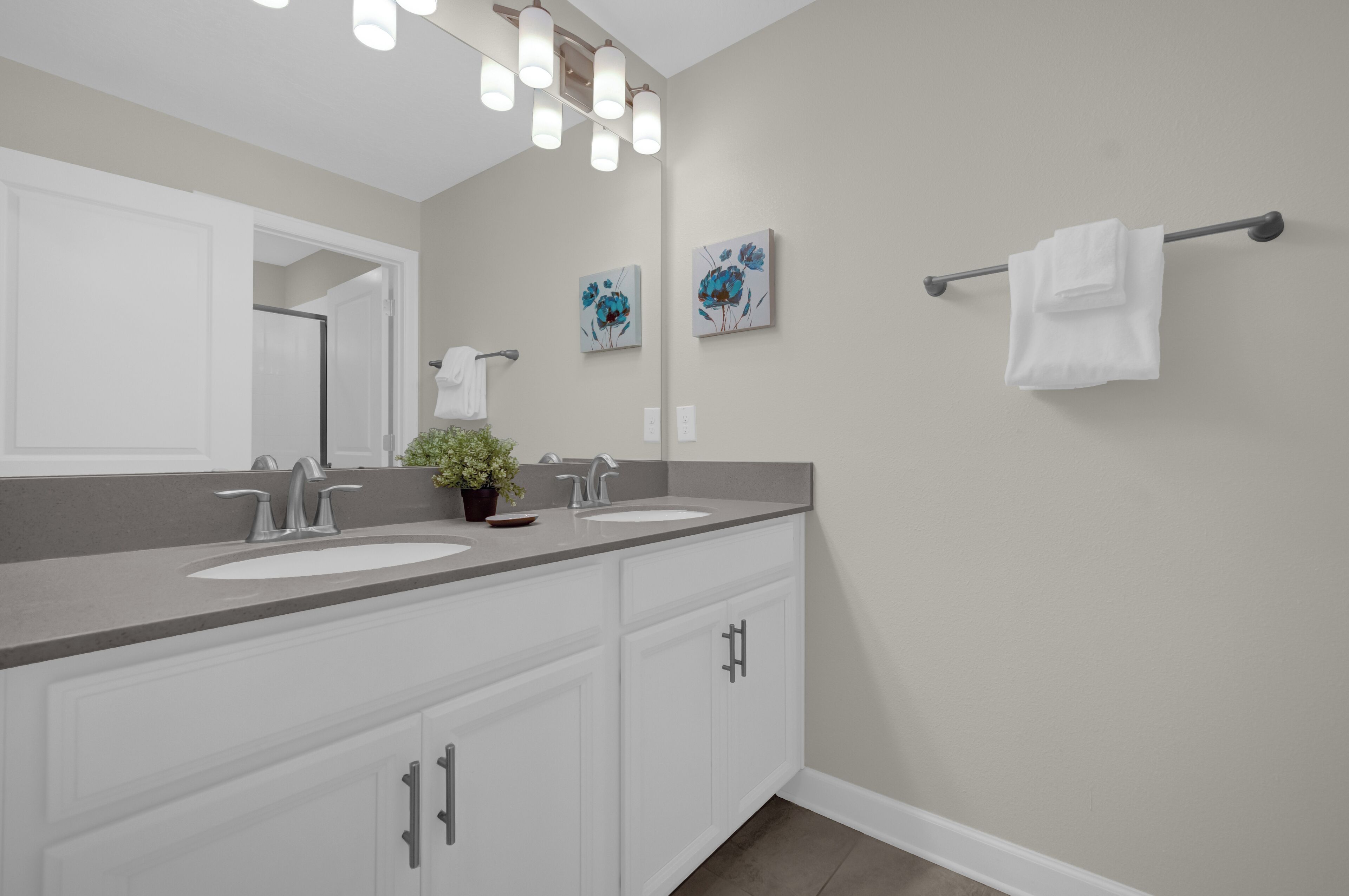 A bathroom with two sinks, a large mirror, and a towel rack.