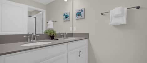 Un baño con dos lavamanos, un espejo grande y un perchero para toallas.