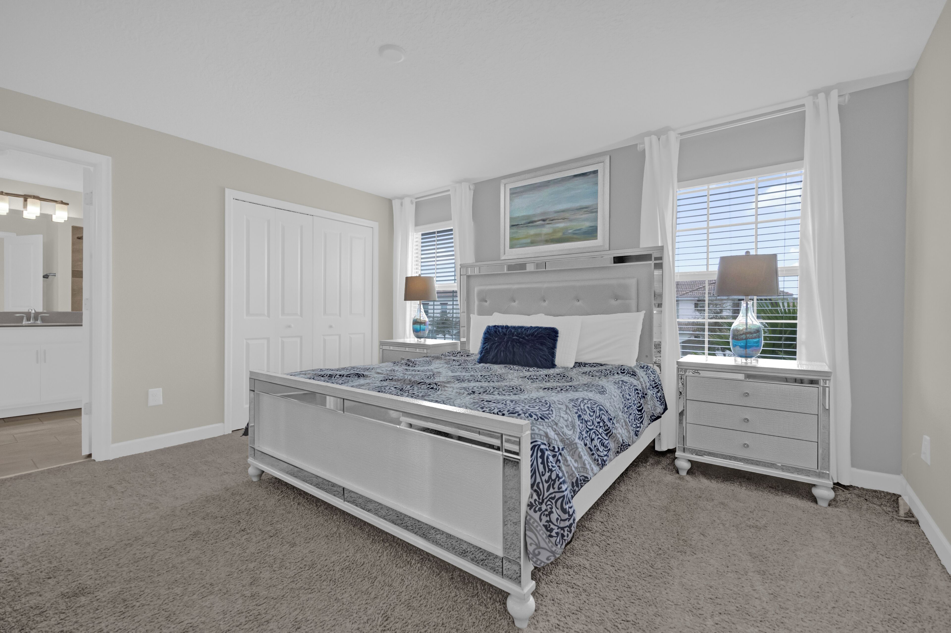 A bedroom with a bed, bedside tables, a dresser, a window with blinds, and a painting on the wall.