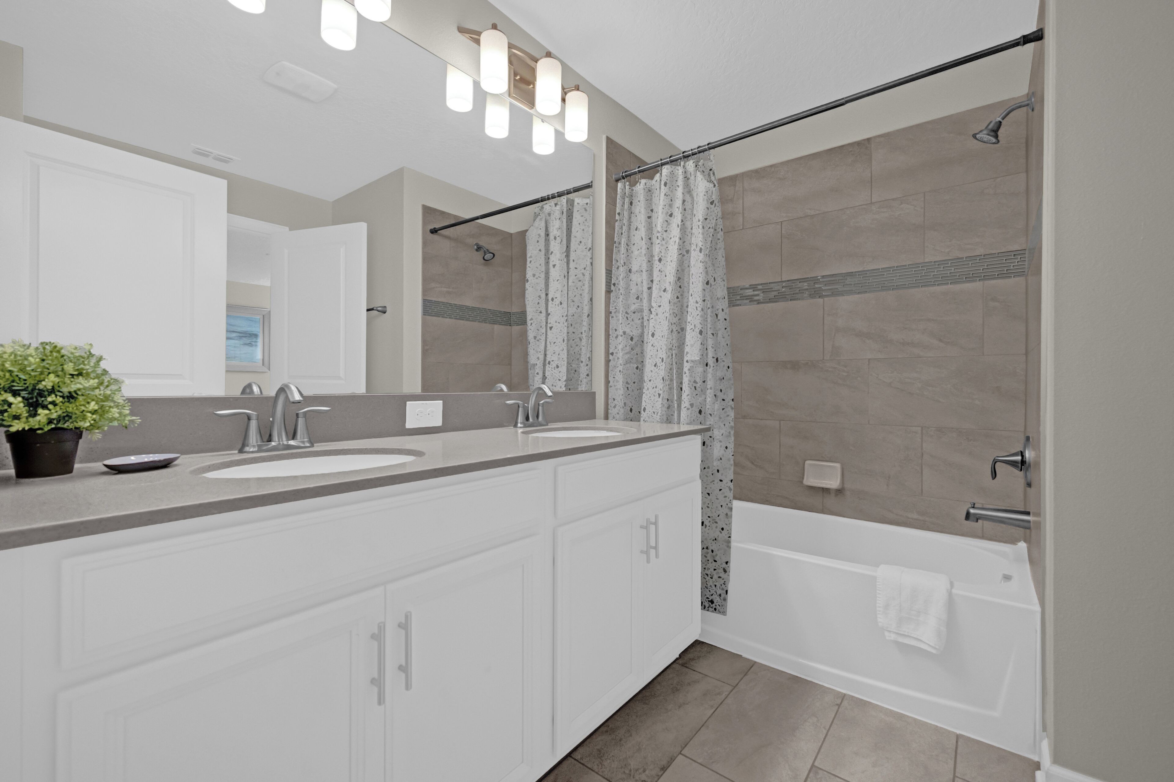 A modern bathroom with a double sink vanity, a bathtub, and a shower with a curtain.
