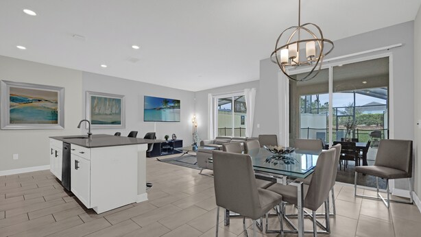 A spacious kitchen with a central island, a dining area with a glass table, and a large sliding glass door leading to an outdoor patio.