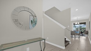 A modern interior with a glass console table, a spiral staircase, and a dining area with chairs and a table.
