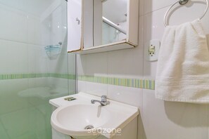 Ein Badezimmer mit einem weißen Waschbecken, einem Spiegel und einem Handtuch an einem Metallring.