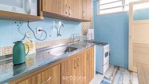 A kitchen with wooden cabinets, a stainless steel sink, a microwave, and a stove.