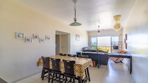 A dining area with a table and chairs, a ceiling fan, and a view of the outdoors.