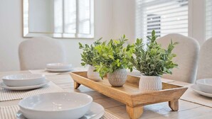 A dining table with white plates, bowls, and a wooden tray with potted plants. - 4BR home with  workspace & parking (Oxford)