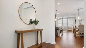 A modern living room with a wooden console table, a round mirror, and a potted plant. - 4BR home with  workspace & parking (Oxford)