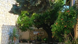 Ein Innenhof mit Steinmauer, einem Schild für 'Boulillon Club', Außenbestuhlung und Kübelpflanzen.