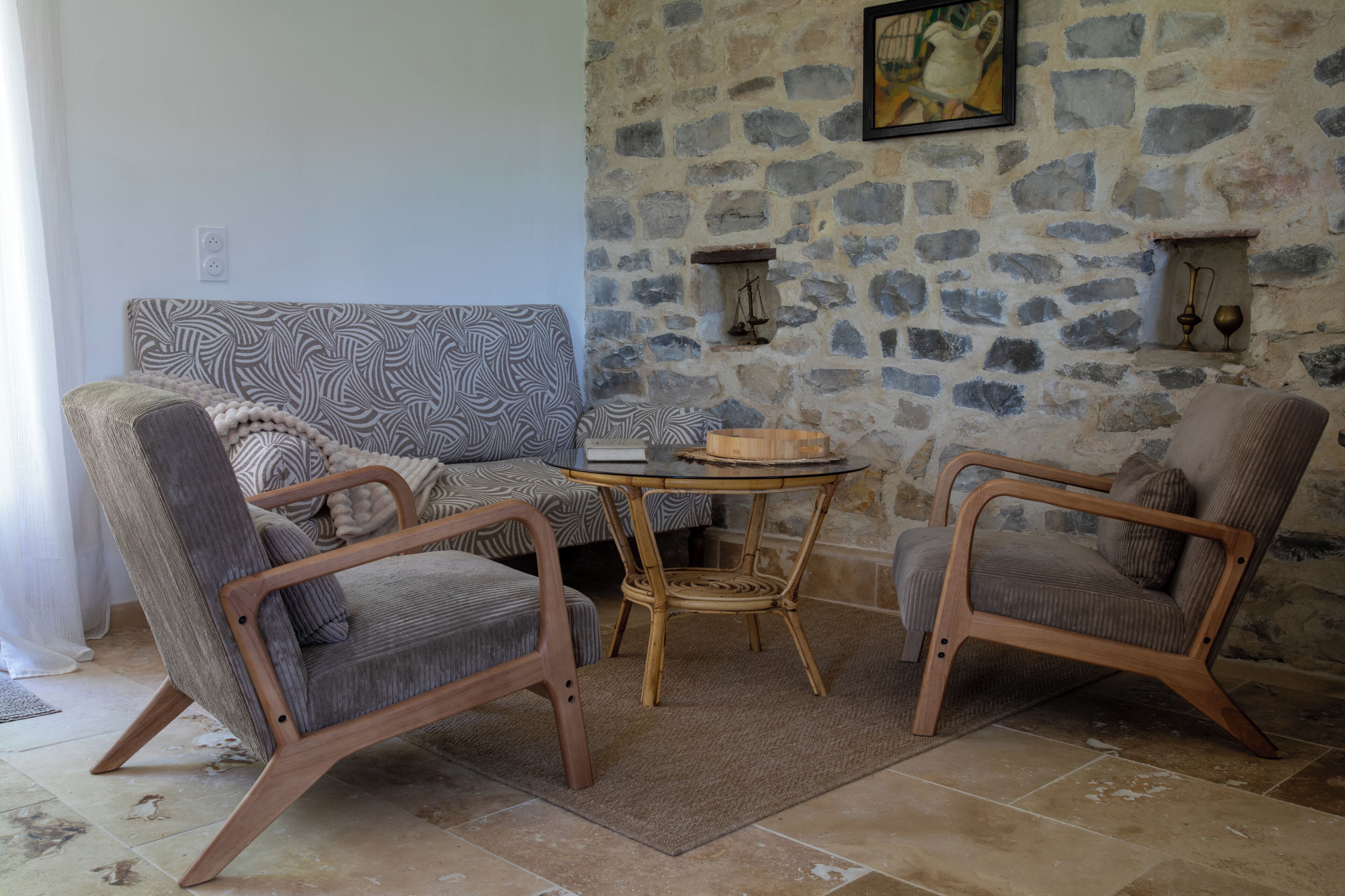 A living room with a stone wall, a patterned sofa, and two wooden chairs.