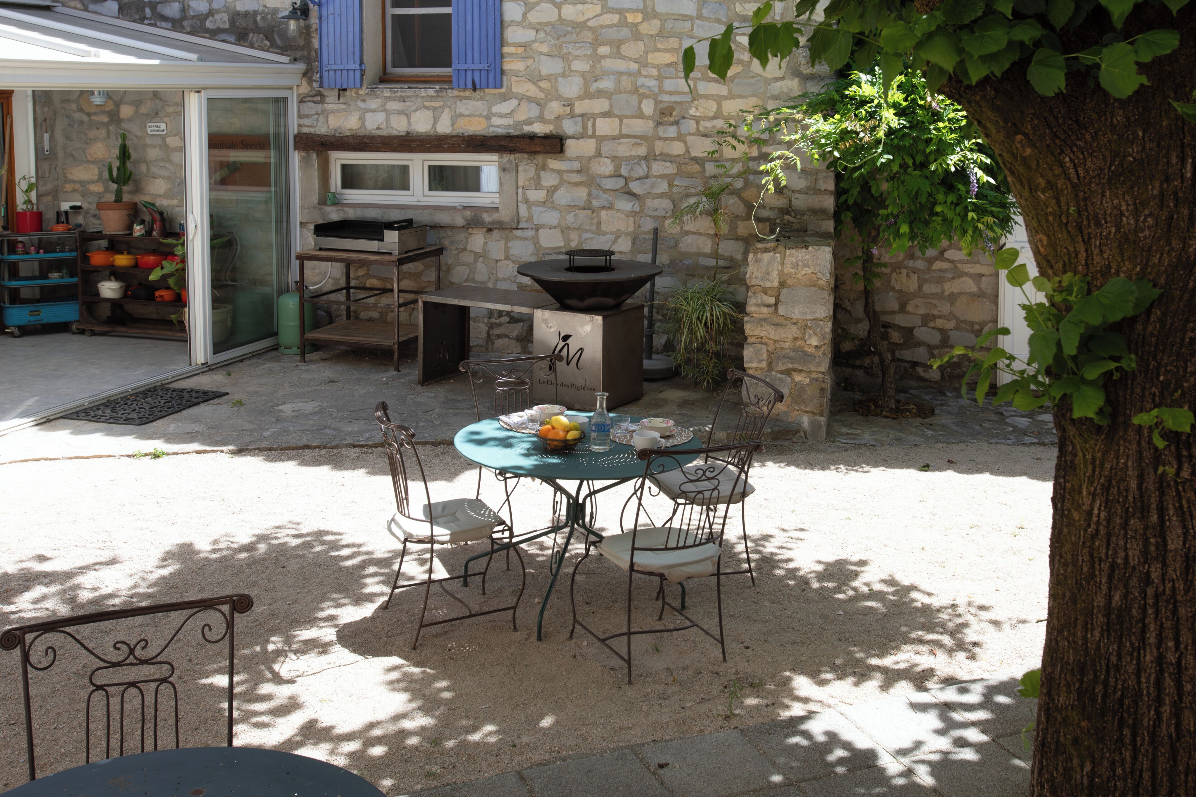 Eine Terrasse im Freien mit Tisch, Stühlen, Grill und einem Blumentopf.
