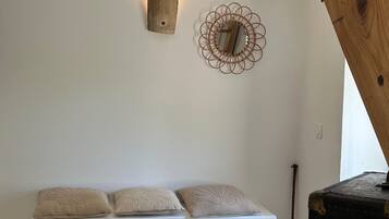 Ein Zimmer mit einer weißen Bank, zwei gewebten Körben, einer Holzdeko und einem Wandspiegel.