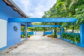 A covered patio area with a blue roof, potted plants, and a view of a gated entrance. - 4BR Home w/ BBQ 100m From Beach Jat0355 (Bombinhas)