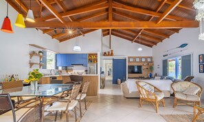 A spacious living area with a high ceiling, a dining table with wicker chairs, a kitchen with blue cabinets, and a TV in the living room. - 4BR Home w/ BBQ 100m From Beach Jat0355 (Bombinhas)