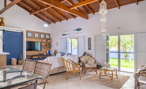 A spacious room with a bed, wicker furniture, a glass table, and a TV. - 4BR Home w/ BBQ 100m From Beach Jat0355 (Bombinhas)