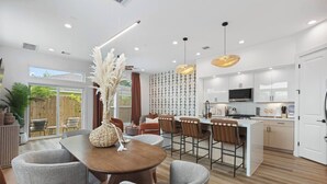A modern kitchen with white cabinets, a central island with bar stools, and pendant lighting. - Luxury 3BR Houston - Near Downtown & Stadiums (Houston)