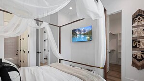 A bedroom with a four-poster bed, a mounted TV, and a wardrobe with a patterned curtain. - Luxury 3BR Houston - Near Downtown & Stadiums (Houston)