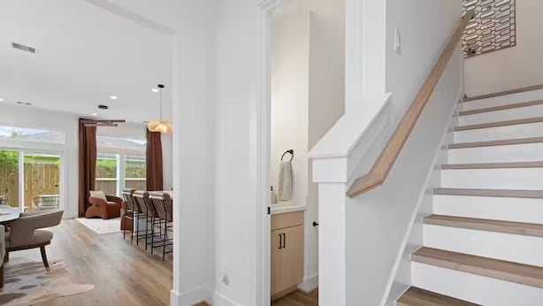 A modern interior with a staircase, a dining area with a view, and a kitchen with wooden cabinets. - Luxury 3BR Houston - Near Downtown & Stadiums (Houston)