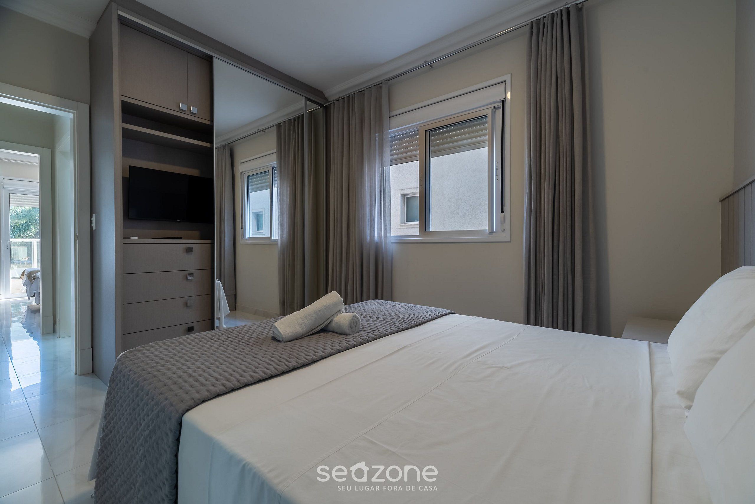 Un dormitorio con cama, armario, ventana y puerta que da a un balcón.