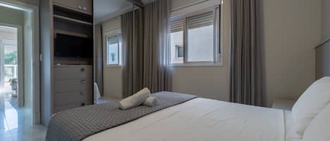A bedroom with a bed, a wardrobe, a window, and a door leading to a balcony.