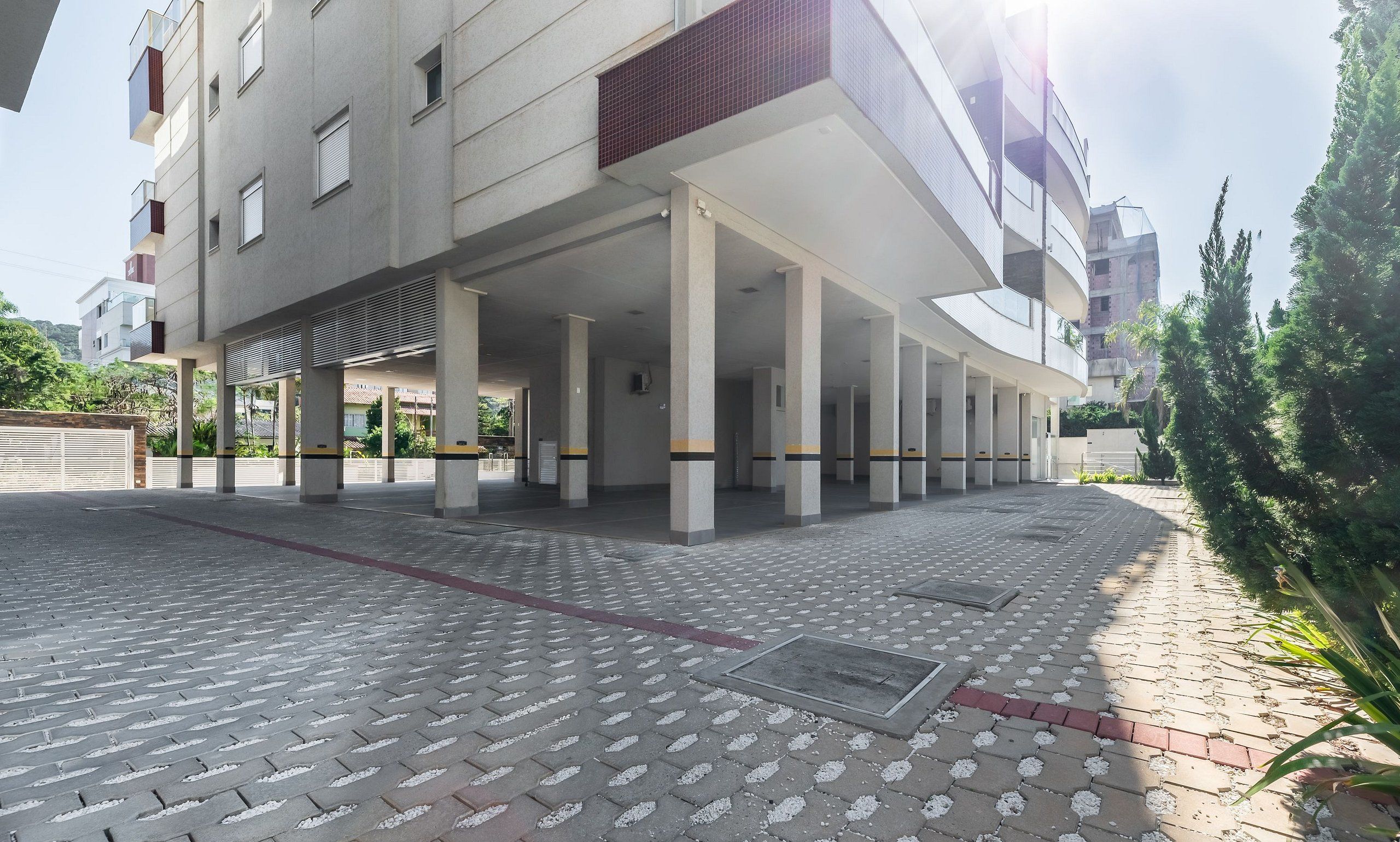 Un edificio moderno con estacionamiento cubierto y un sendero pavimentado.