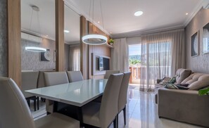 Una sala moderna con comedor, sofá y televisor.