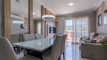 Una sala moderna con comedor, sofá y televisor.