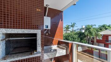 Un balcón con un muro de azulejos, un calentador de agua y un lavamanos pequeño.