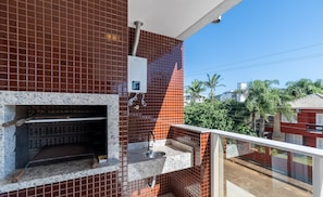 A balcony with a tiled wall, a water heater, and a small sink.