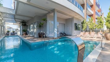 Un hotel moderno con una amplia piscina cubierta, tumbonas y plantas en macetas.