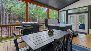 A covered outdoor area with a wooden deck, a grill, a hot tub, and a table with chairs. - Kid Friendly! Foosball, Playset, 3 Arcades (Broken Bow)