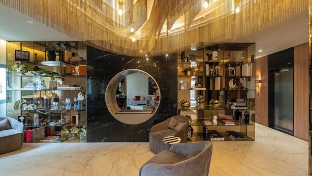 Ein modernes Interieur mit einem großen, runden Spiegel, Marmorböden und verschiedenen Dekorationsgegenständen auf Regalen.