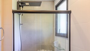 Un baño moderno con cabina de ducha de vidrio, un perchero y un estante de vidrio.