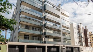 Un edificio residencial de varios pisos con balcones, una zona de garaje y cielo despejado.