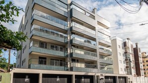 Un immeuble résidentiel à plusieurs étages, doté de balcons, d’un espace de garage et surplombant un ciel dégagé.