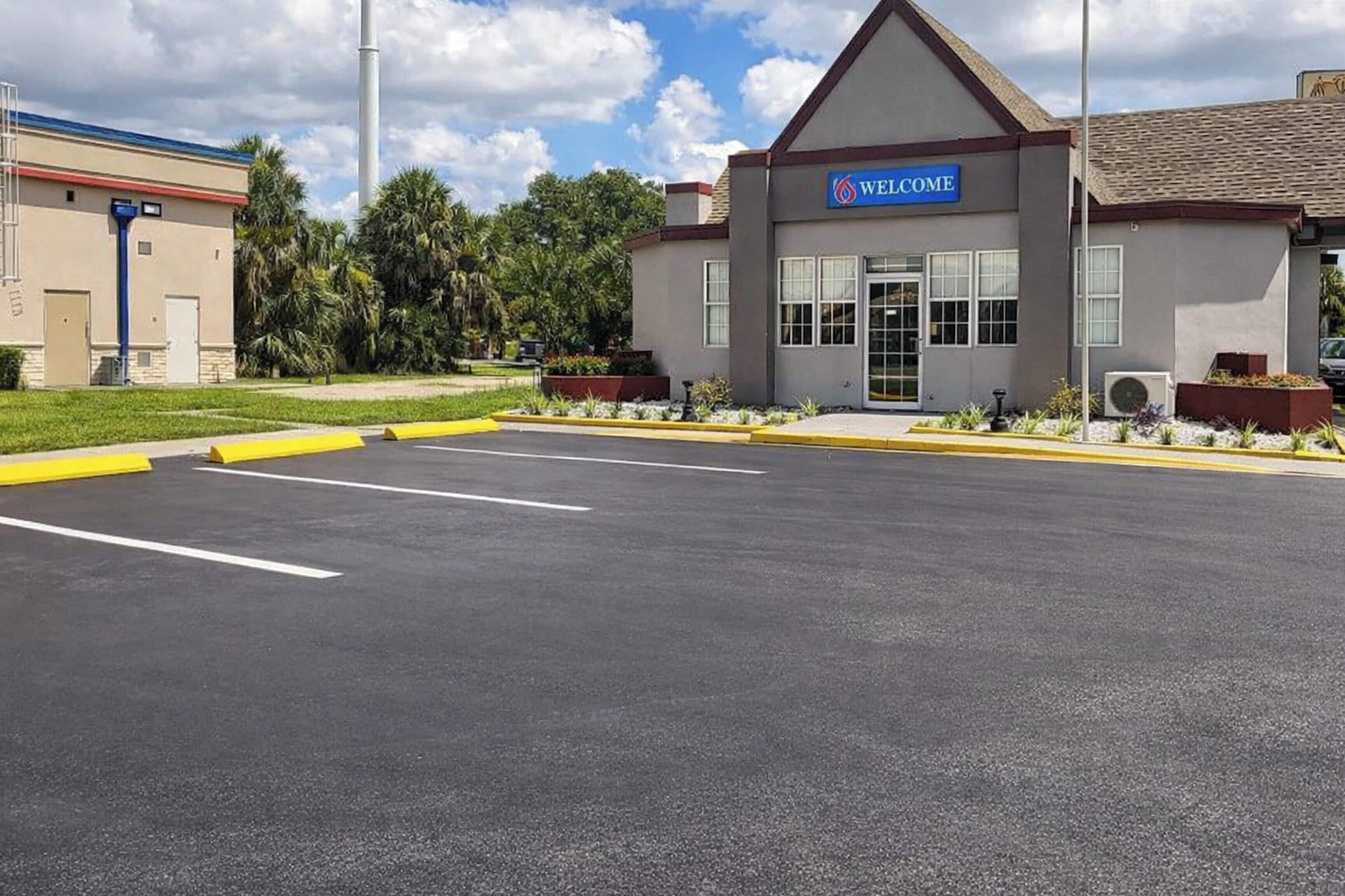 A building with a 'WELCOME' sign, a parking lot, and a clear sky.