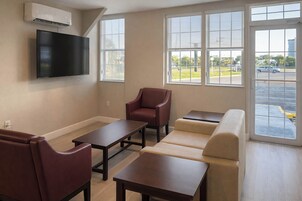 Una sala de estar moderna con un televisor de pantalla plana montado en la pared, un sofá, un sillón y una mesa de centro.