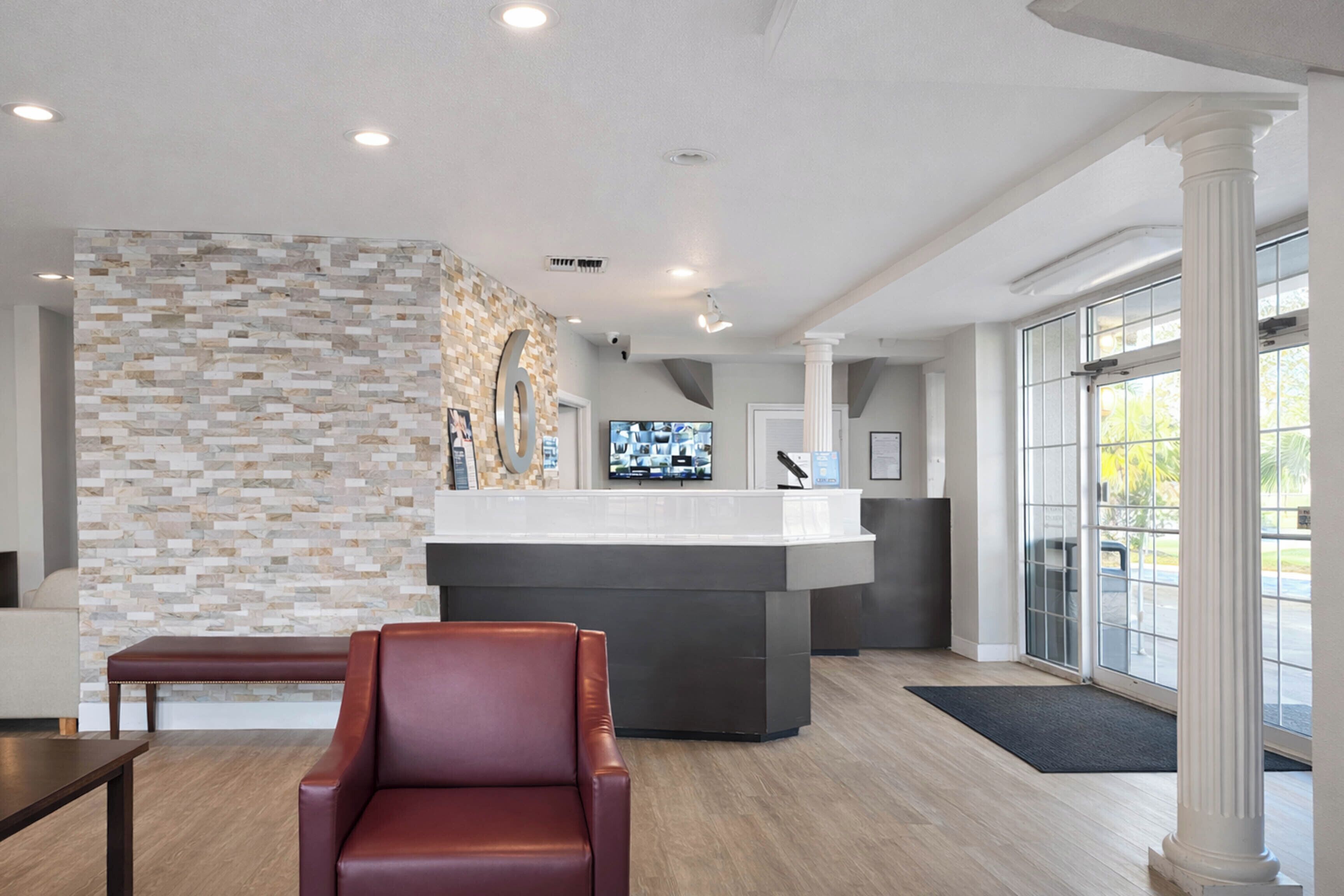 A reception area with a stone wall, a reception desk, a leather chair, and a large window.